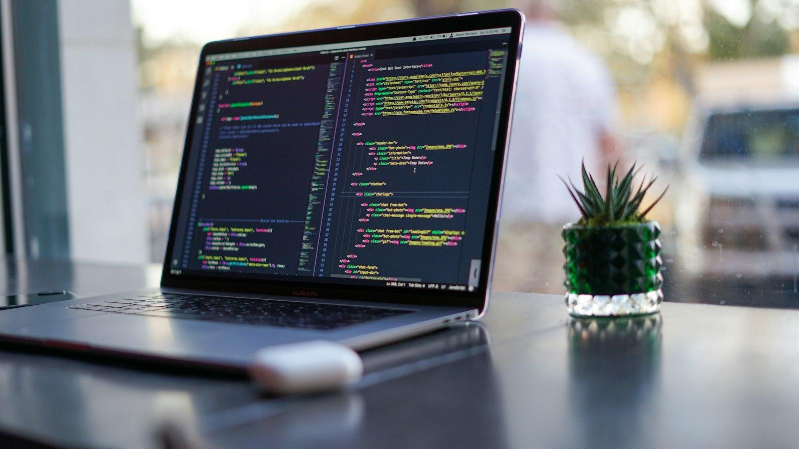 A laptop on a table showing lines of code